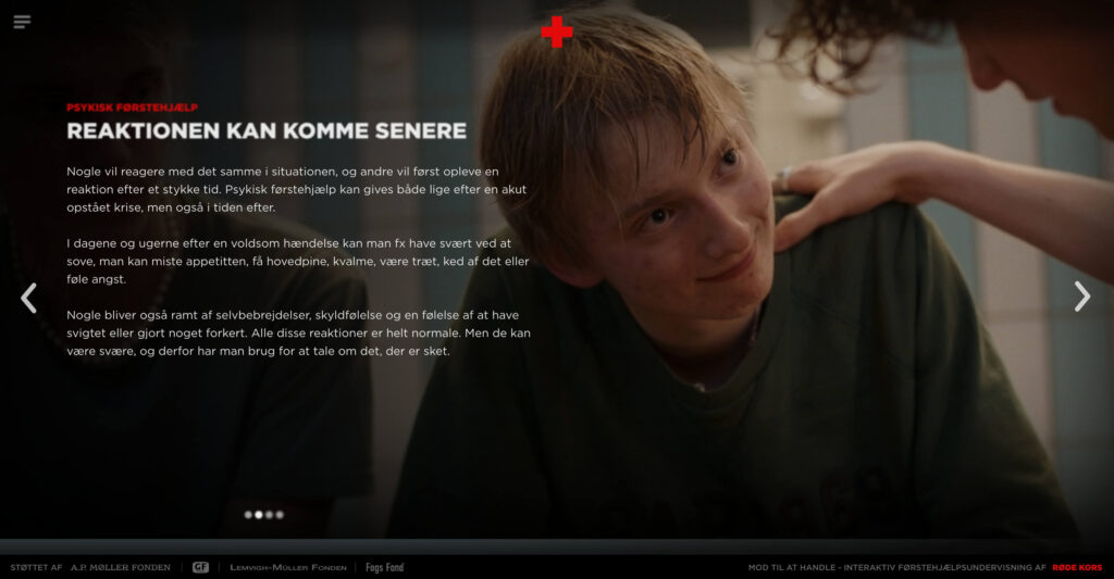 An informational screen from the campaign titled 'PSYKISK FØRSTEHJÆLP' (Psychological First Aid) with the subtitle 'REAKTIONEN KAN KOMME SENERE' (The reaction may come later). The background shows a comforting hand resting on a teenager's shoulder in a locker room. The text describes how people can experience delayed crisis reactions, such as insomnia, guilt, or anxiety, in the days and weeks following a traumatic event.